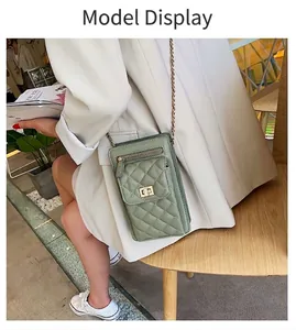 Green quilted diamond pattern crossbody phone bag with metal chain strap on model