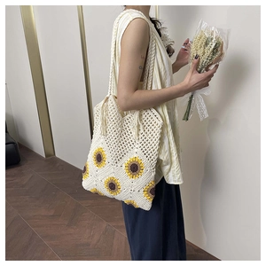 Detail of hand-woven sunflower tote bag in cream white with tassels and floral motifs