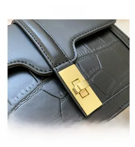 Détail de la texture crocodile noire et du fermoir en métal doré brillant sur le sac