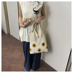Detail of handmade crochet tote bag featuring sunflower patterns and woven fringe accents