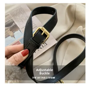 Détail de la ceinture noire en simili cuir avec boucle dorée et coutures sur tissu