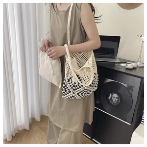 Detail of hand-crocheted shoulder bag with contrast knit patterns and drawstring inner pouch
