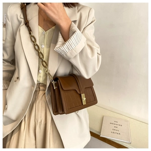 Petit sac carré marron à motif crocodile avec fermoir en métal porté par un modèle