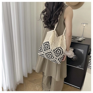 Detail of hand-crocheted black and white floral tote bag with fringe tassels on shoulder