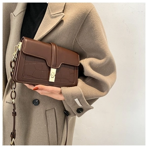 Détail d'un sac à bandoulière marron foncé à texture pierre avec fermoir doré