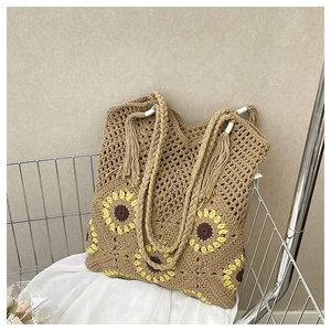 Detail of sunflower crochet tote bag with braided handles and decorative fringe tassel