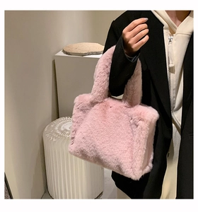 Plush pink faux fur tote bag styled with a long black winter coat and a beige hoodie
