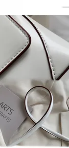 Detailed close-up of white leather texture, brown edge paint, and cylindrical handle