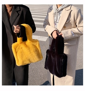 Close-up of fluffy faux fur tote bags in yellow and black during an urban street shoot