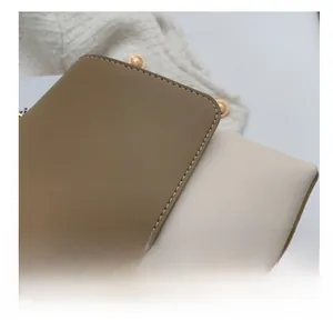 Gros plan sur les surpiqûres blanches et les ferrures dorées du sac en cuir bicolore