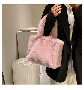 Pink plush tote bag held by a model, showing the fluffy texture and soft handle detail