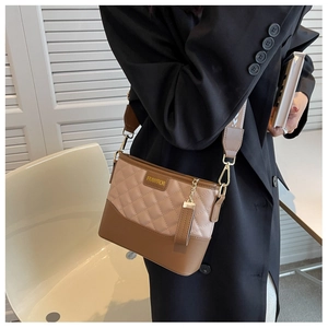 Detail of rhombic quilted crossbody bag with brown leather trim and metal brand logo