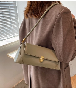 Detail of light khaki baguette bag with golden buckle worn on shoulder with blazer