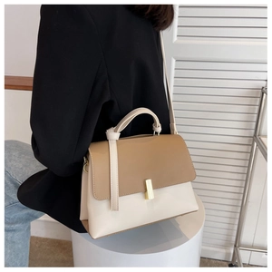 Détail d'un sac à main bicolore en cuir avec boucle dorée et bandoulière réglable