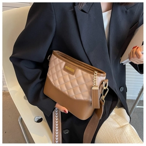 Close-up of quilted two-tone leather bag with arrow embroidered strap and gold chain