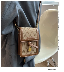 Detailed view of a brown monogram crossbody bag worn with a grey blazer for daily style