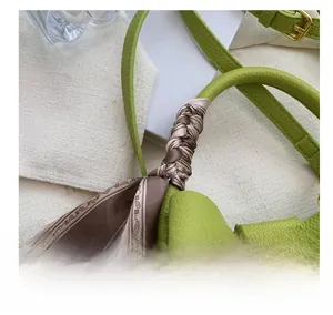 Détail du sac à main vert en cuir grainé avec foulard en soie imprimé sur la poignée