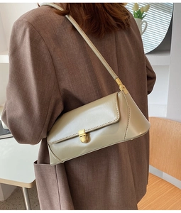 Detail of beige square baguette bag with gold buckle worn with a brown blazer