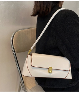 Detail shot of a white baguette bag with gold lock on a model in tweed jacket