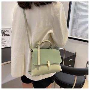 Vue détaillée d'un sac à bandoulière vert clair sur un mannequin dans un bureau moderne