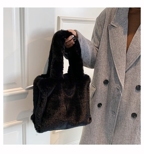 Detail of black faux fur tote bag paired with a grey herringbone coat for autumn fashion