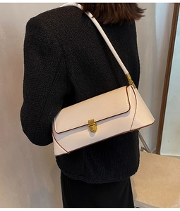Close-up of a white rectangular shoulder bag featuring a gold buckle and red edge paint