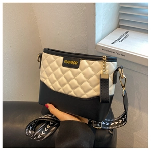Detail of quilted leather bucket bag featuring wide geometric strap and golden chain