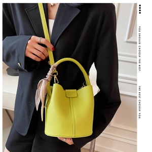 Détail du sac seau jaune vif avec texture en cuir grainé et foulard en soie décoratif