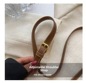 Detail of adjustable dark brown faux leather shoulder strap with a gold metal buckle
