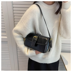 Detail of black patent leather shoulder bag with gold metal buckle on white background