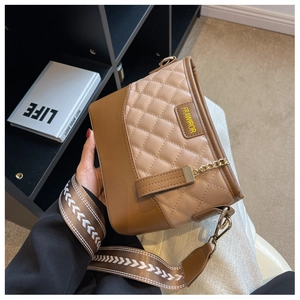 Close-up of brown quilted hobo bag with adjustable wide strap and gold logo plate