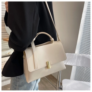 Détail du sac à main minimaliste en cuir beige avec fermoir doré et poignée élégante