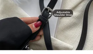 Detail of adjustable black leather shoulder strap with silver metal buckle on tote bag