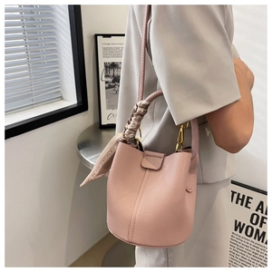 Sac seau en cuir rose grainé avec poignée décorée d'un foulard et détails dorés chic