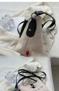 Detailed close-up of canvas tote with black leather straps and silver ring hardware