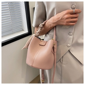Détail du sac seau en cuir rose avec foulard floral enroulé autour de la poignée