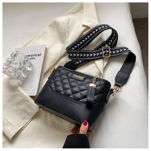 Detail of black quilted leather crossbody bag with chic patterned wide shoulder strap