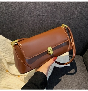 Detailed view of caramel brown leather baguette bag with premium golden metal buckle