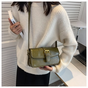 Detail of vintage olive green flap shoulder bag with gold metal buckle and leather texture