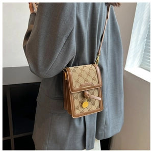 Detail of a brown leather crossbody phone bag featuring monogram fabric and gold hardware
