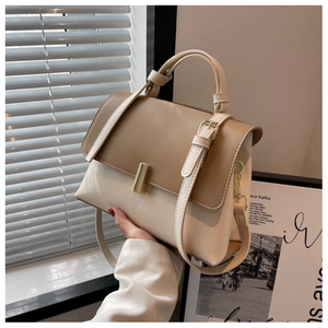 Détail d'un sac bandoulière bicolore chic avec boucle dorée et poignée ronde