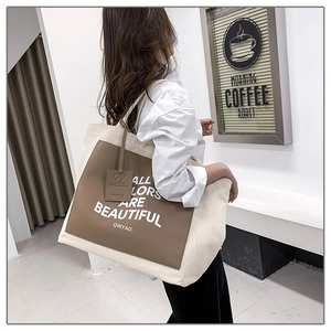 Detail of canvas tote bag with brown leather patch and white slogan for daily commute