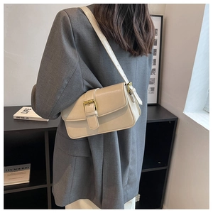Detail view of beige crossbody bag with gold buckle on gray blazer outfit