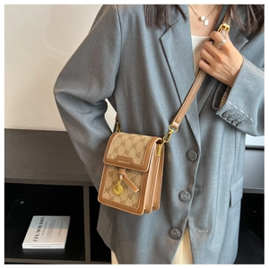 Vertical vintage monogram crossbody bag featuring brown leather trim and a gold pendant