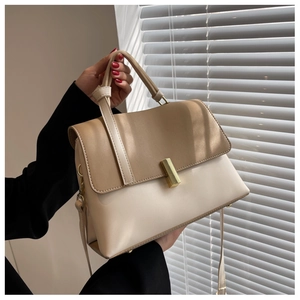 Détail d'un sac à bandoulière bicolore kaki et beige avec fermoir rotatif en métal doré