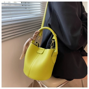 Sac seau en cuir grainé vert citron avec foulard en soie sur blazer noir