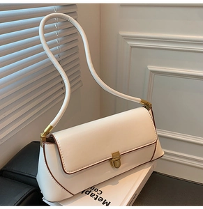 Detail view of cream leather shoulder bag with gold square buckle and brown edges