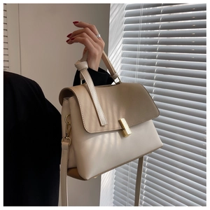 Détail d'un sac bandoulière bicolore élégant avec boucle dorée et jeu d'ombre doux
