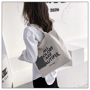 Detail of canvas tote bag with black slogan All Colors Are Beautiful and logo