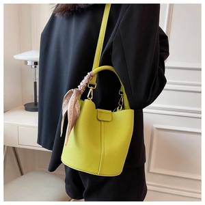 Détail du sac seau en cuir vert citron avec foulard en soie et finitions dorées
